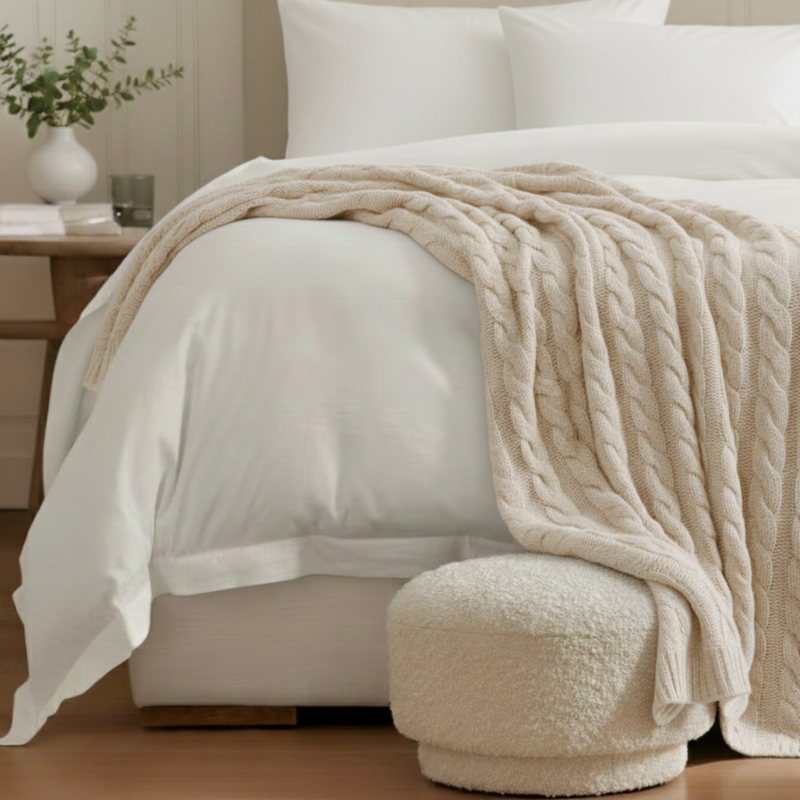 Cashmere cable knit throw in cream styled on blanket